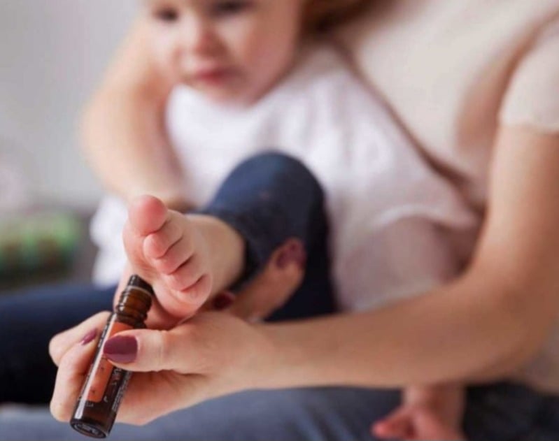 Application d’huile essentielle sur le pied d’un enfant